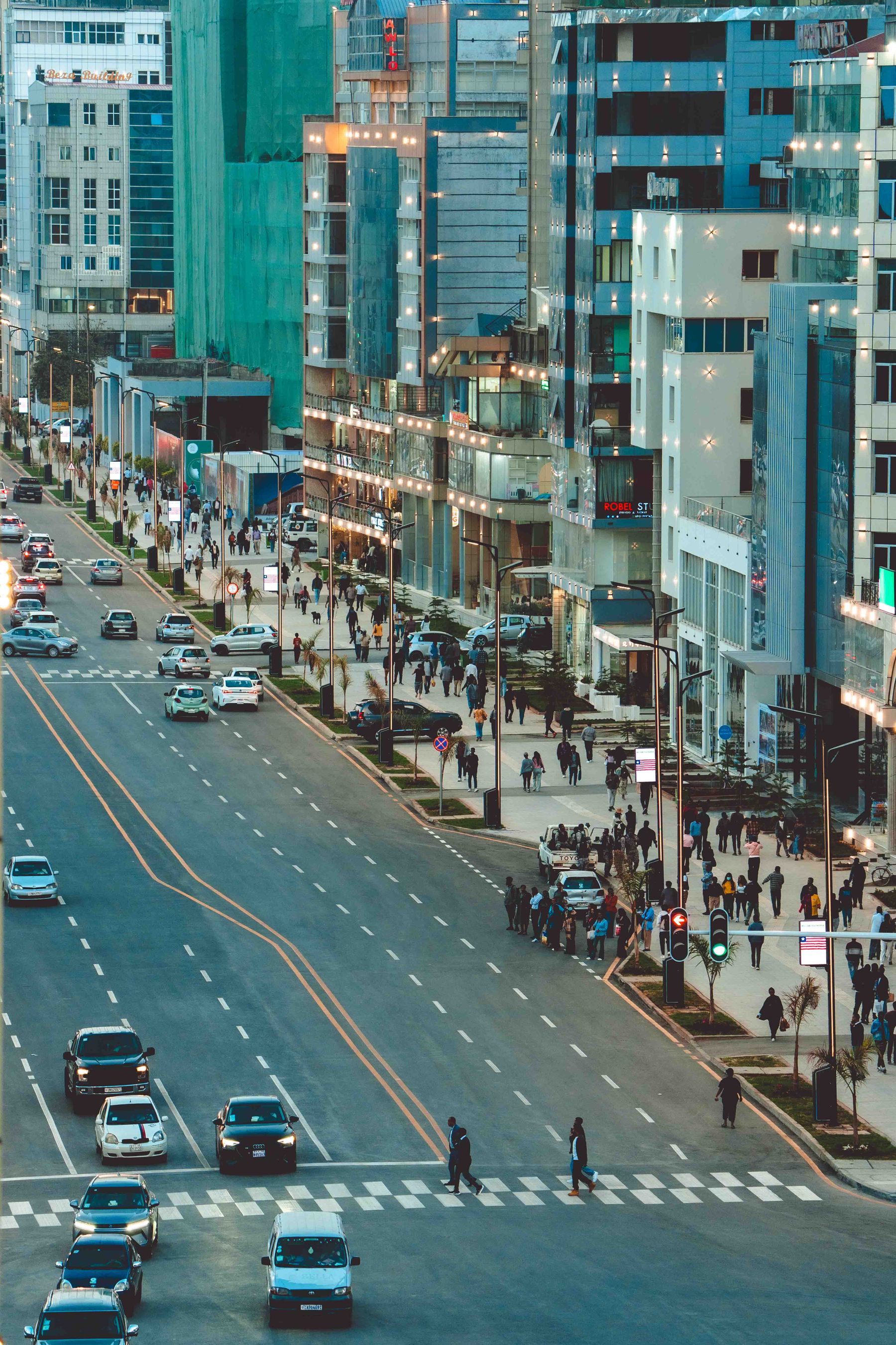 Traffic and pedestrians moving through a modern Addis Ababa business district at dusk