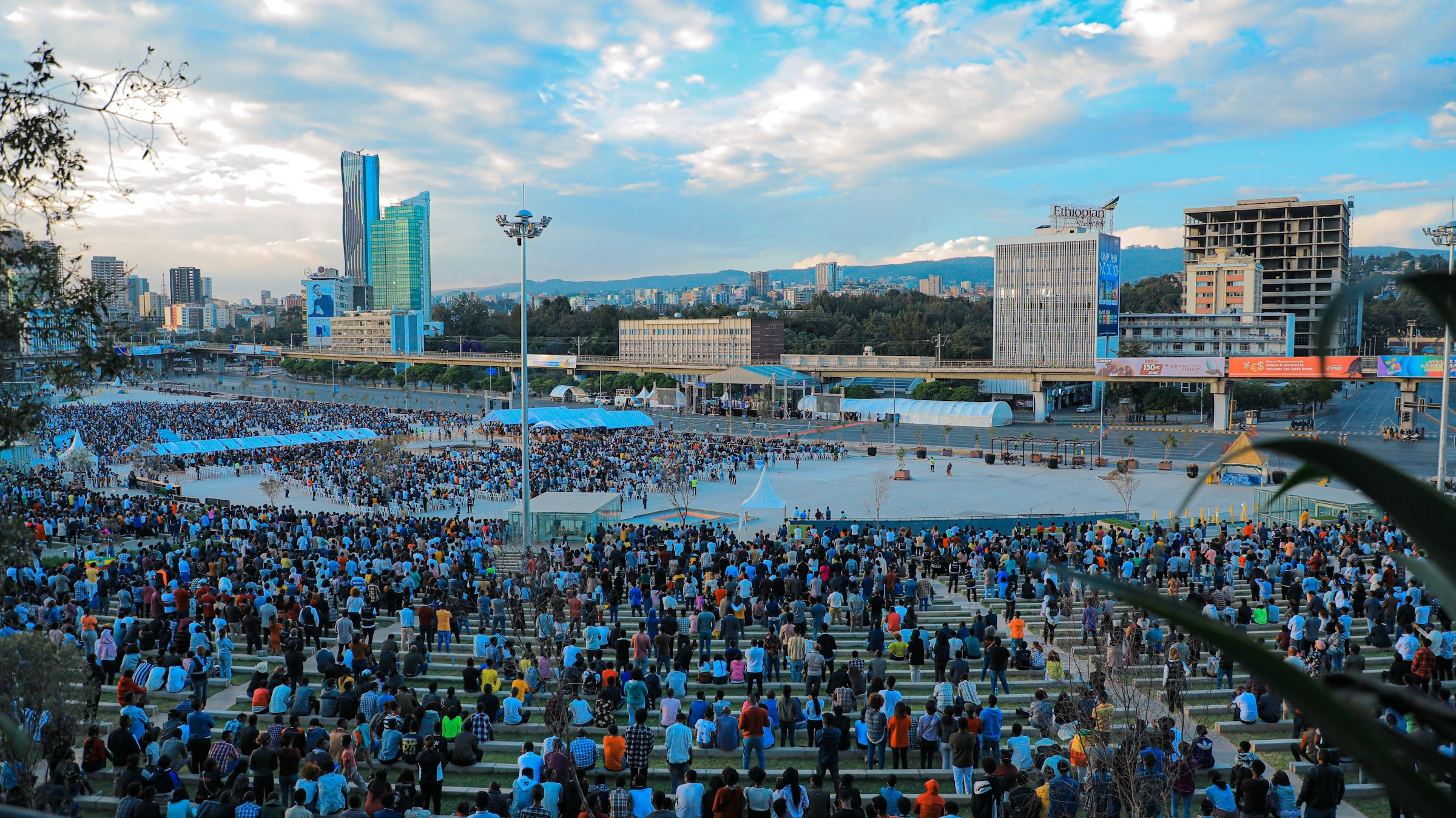 A large public gathering in Addis Ababa with the city skyline and Entoto hills beyond