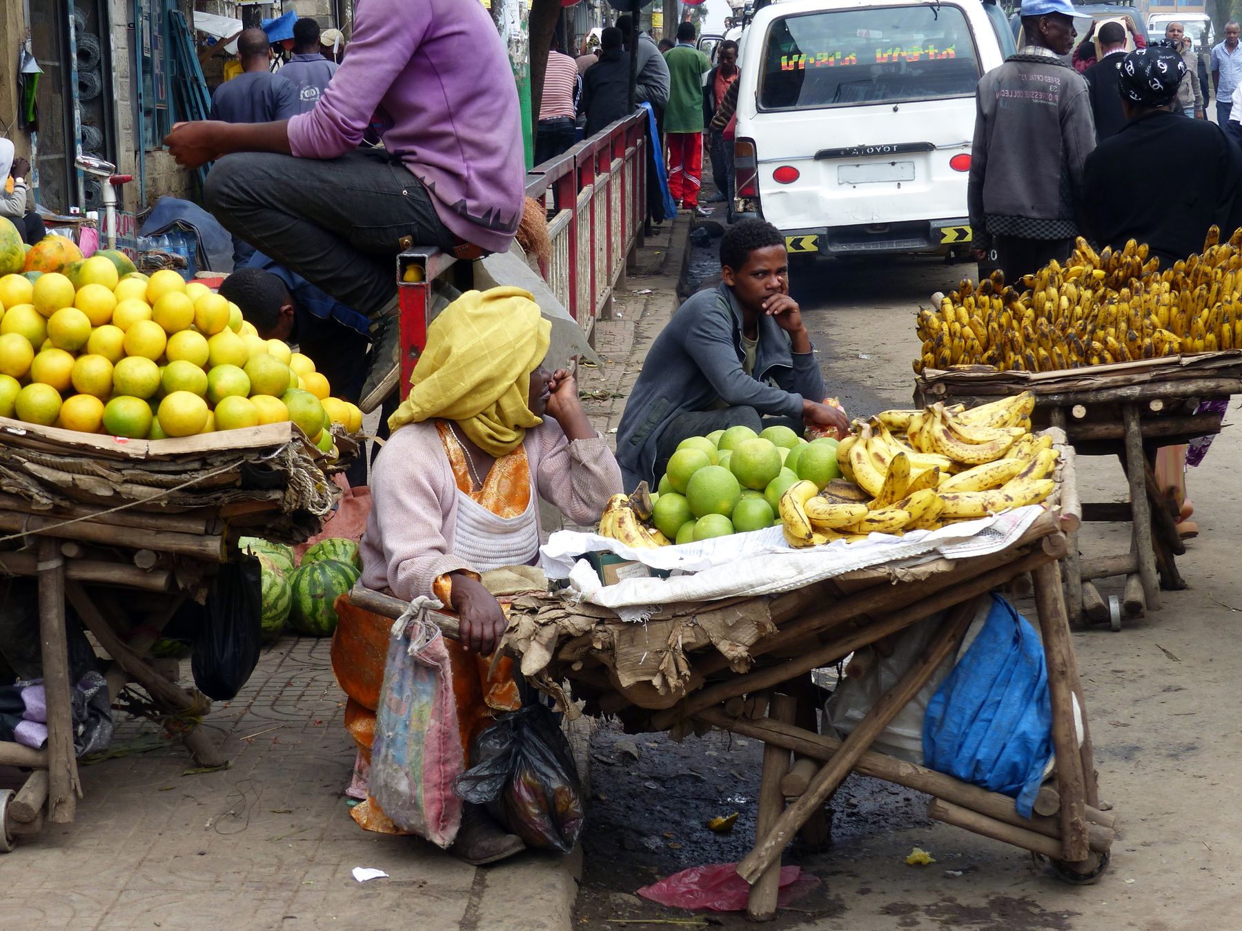 Fruit vendors and customers on a busy Addis Ababa market street