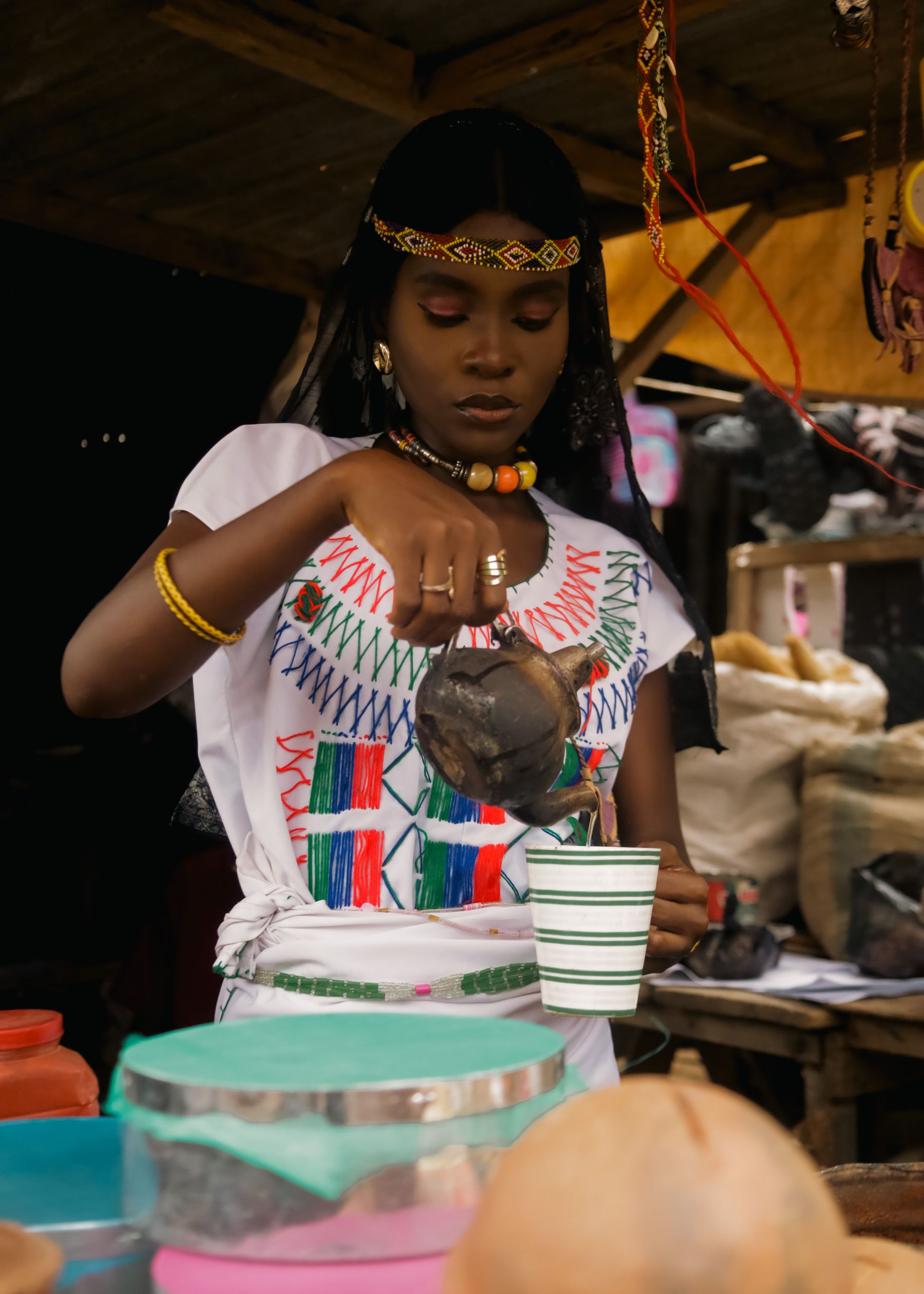 A woman in traditional Ethiopian clothing pouring coffee from a clay jebena